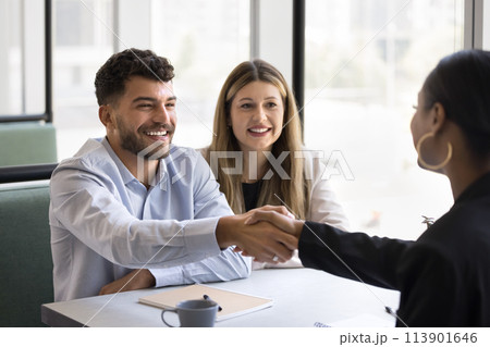 Cheerful young couple shaking hands with African American lawyer 113901646