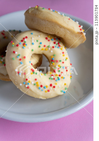 Small homemade donuts covered in white chocolate and colorful toppings Small homemade donuts covered in white chocolate and colorful toppings 113901784