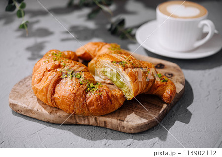 Fresh pistachio croissants and coffee on table 113902112
