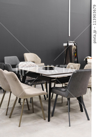 Gray wooden table combined with beige wooden chairs with soft fabric upholstery. Blue and black porcelain plates on the table Gray wooden table combined with beige wooden chairs with soft fabric upholstery. Blue and black porcelain plates on the table 113903679