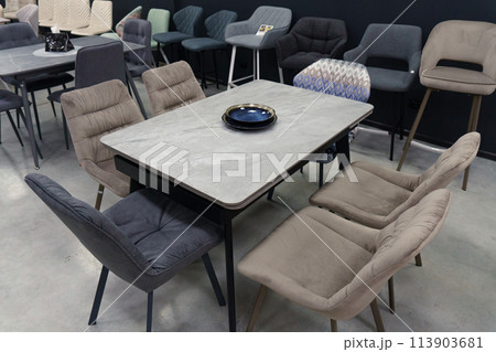 Gray wooden table combined with beige wooden chairs with soft fabric upholstery. Blue and black porcelain plates on the table Gray wooden table combined with beige wooden chairs with soft fabric upholstery. Blue and black porcelain plates on the table 113903681