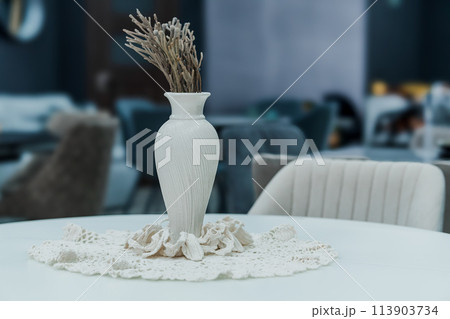 White wooden table complete with white wooden chairs with soft fabric upholstery. Milky porcelain vase on the table White wooden table complete with white wooden chairs with soft fabric upholstery. Milky porcelain vase on the table 113903734