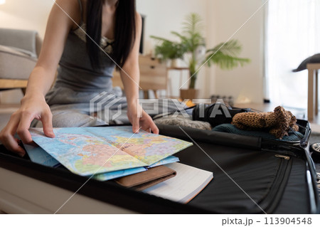 Asian woman packing suitcase or luggage and planning to travel on summer vacation on map 113904548
