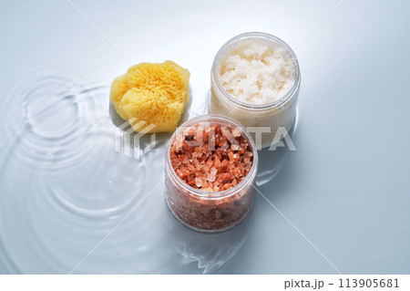 Body scrub, bath salt and natural sponge on a blue background with water. 113905681