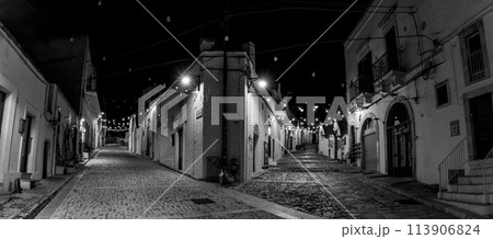 Scenic abandoned street in the Trulli district of Alberobello at night, Italy 113906824