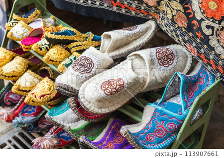 An assortment of decorated Uzbek felt slippers is displayed at a street bazaar 113907661