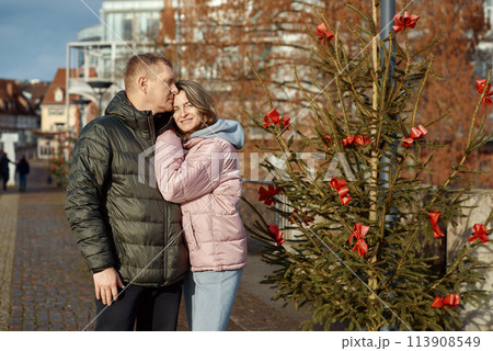 couple in love A guy and a girl hugging on the street of the old European town of Bietigheim-Bissingen in Germany on Christmas Eve. The city streets are decorated with Christmas trees and New Year's couple in love A guy and a girl hugging on the street of the old European town of Bietigheim-Bissingen in Germany on Christmas Eve. The city streets are decorated with Christmas trees and New Year's 113908549