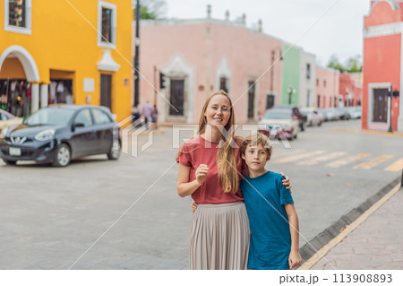Mother and son tourists explore the vibrant streets of Valladolid, Mexico, immersing herself in the rich culture and colorful architecture of this charming colonial town 113908893