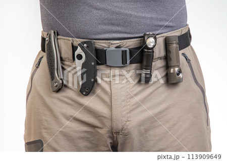 folding knife and a flashlight with clips on the belt of a tourist trekking trousers. EDC items 113909649