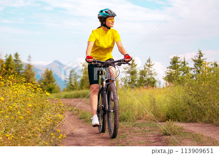 Beautiful woman cyclist rides a bicycle in nature. Healthy lifestyle and sports. Leisure and hobbies Beautiful woman cyclist rides a bicycle in nature. Healthy lifestyle and sports. Leisure and hobbies 113909651
