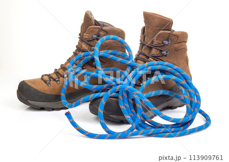 trekking boots for hiking next to a climbing rope on a white background. Travel and Hiking Equipment 113909761