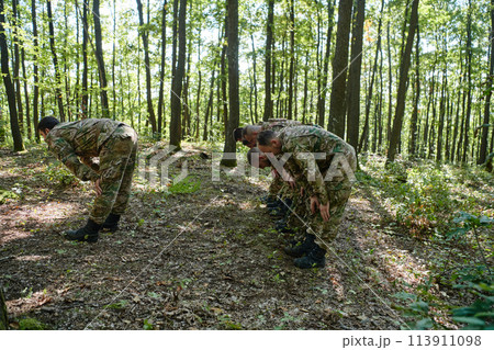 A dedicated group of soldiers engages in Islamic prayer amidst the challenging and perilous conditions of a military operation in dense forested areas 113911098