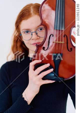 Stunning Redhead Musician Poses with Violin in Captivating Portrait 113911140
