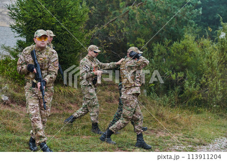 A group of elite soldiers leads captives through a military camp, showcasing a tense atmosphere of detention and security operations A group of elite soldiers leads captives through a military camp, showcasing a tense atmosphere of detention and security operations 113911204