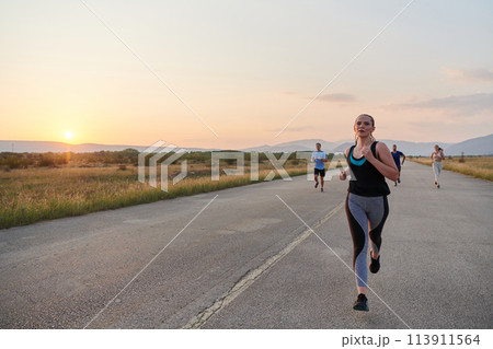A diverse group of runners trains together at sunset. 113911564