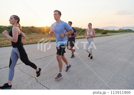 A diverse group of runners trains together at sunset. 113911900