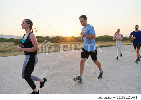 A diverse group of runners trains together at sunset. A diverse group of runners trains together at sunset. 113912041