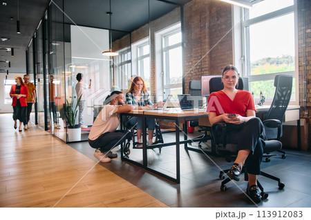 A diverse group of business professionals collaborates in a modern startup coworking center, utilizing a mix of paper-based and technological tools such as mobile phones and computers  113912083