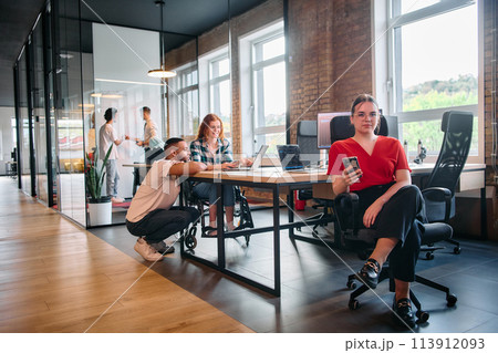 A diverse group of business professionals collaborates in a modern startup coworking center, utilizing a mix of paper-based and technological tools such as mobile phones and computers A diverse group of business professionals collaborates in a modern startup coworking center, utilizing a mix of paper-based and technological tools such as mobile phones and computers 113912093