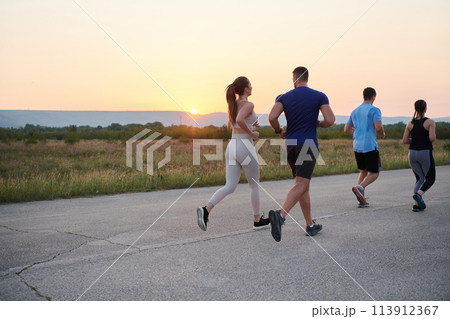 A diverse group of runners trains together at sunset. A diverse group of runners trains together at sunset. 113912367