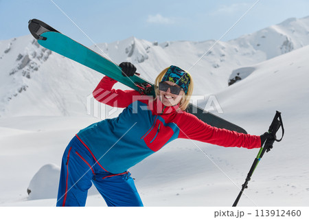 A professional woman skier rejoices after successfully climbing the snowy peaks of the Alps 113912460
