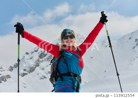 A professional woman skier rejoices after successfully climbing the snowy peaks of the Alps 113912554