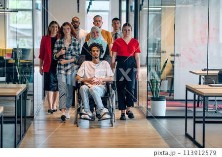A diverse group of young business people congregates within a modern startup's glass-enclosed office, featuring inclusivity with a person in a wheelchair, an African American young man, and a hijab A diverse group of young business people congregates within a modern startup's glass-enclosed office, featuring inclusivity with a person in a wheelchair, an African American young man, and a hijab 113912579