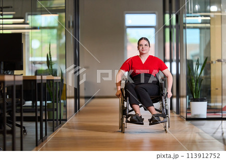 A modern young businesswoman in a wheelchair is surrounded by an inclusive workspace with glass-walled offices, embodying determination and innovation in the business world A modern young businesswoman in a wheelchair is surrounded by an inclusive workspace with glass-walled offices, embodying determination and innovation in the business world 113912752