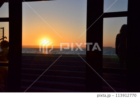 夕焼けと共に思いを馳せる 窓枠に捉えた黄昏の時 海を背に夕陽を望む 夕焼けと共に思いを馳せる 窓枠に捉えた黄昏の時 海を背に夕陽を望む 113912770