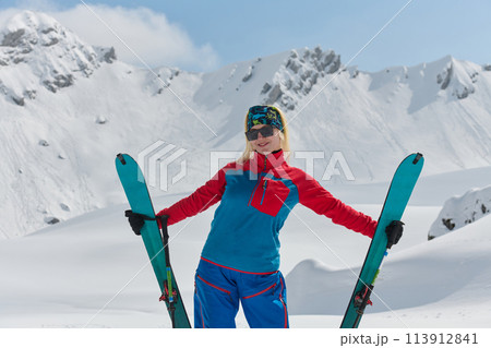A professional woman skier rejoices after successfully climbing the snowy peaks of the Alps 113912841