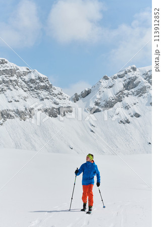 A Skier Scales a Treacherous Alpine Peak 113912852