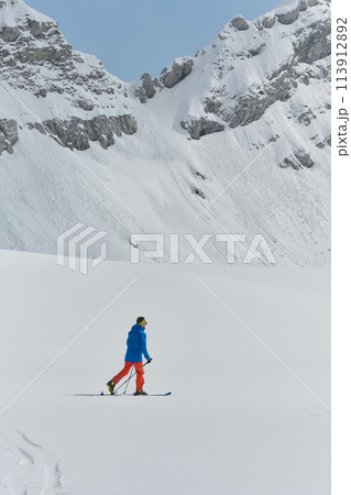 A Skier Scales a Treacherous Alpine Peak 113912892