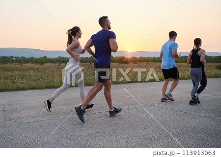 A diverse group of runners trains together at sunset. A diverse group of runners trains together at sunset. 113913063