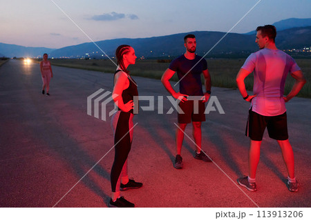 Diverse Athletes Unwind: Post-Marathon Rest Under Red Nighttime Glow. Diverse Athletes Unwind: Post-Marathon Rest Under Red Nighttime Glow. 113913206