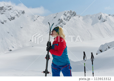 A Professional Female Skier Celebrates Success by Symbolically Licking Her Skis atop the Snowy Alps A Professional Female Skier Celebrates Success by Symbolically Licking Her Skis atop the Snowy Alps 113913312