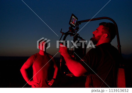 Nighttime Capture: Professional Videographer Films Athletes Running in Red-Lit Darkness 113913652