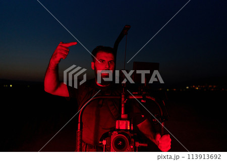 Nighttime Capture: Professional Videographer Films Athletes Running in Red-Lit Darkness Nighttime Capture: Professional Videographer Films Athletes Running in Red-Lit Darkness 113913692