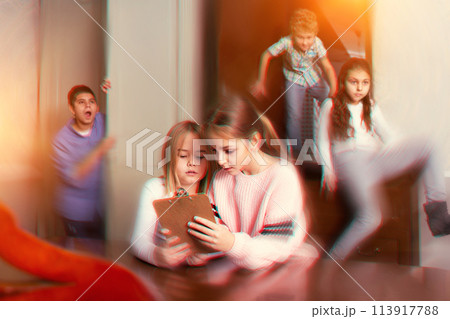 Two preteen girls solving riddles in quest room, toned image Two preteen girls solving riddles in quest room, toned image 113917788