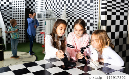 Tween girls solving conundrum in quest room stylized under chessboard 113917892