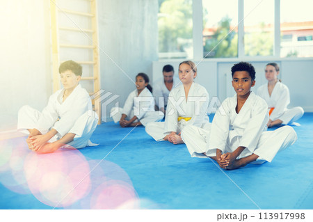 African boy stretching in butterfly pose during group martial arts training African boy stretching in butterfly pose during group martial arts training 113917998