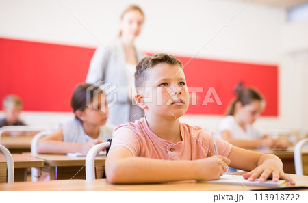 Schoolboy sitting in classroom during lesson in elementary school Schoolboy sitting in classroom during lesson in elementary school 113918722