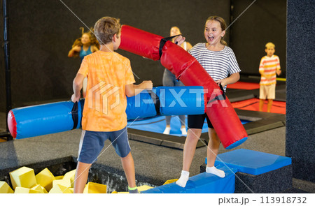 Team of friends playing with inflatable sticks in amusement park Team of friends playing with inflatable sticks in amusement park 113918732
