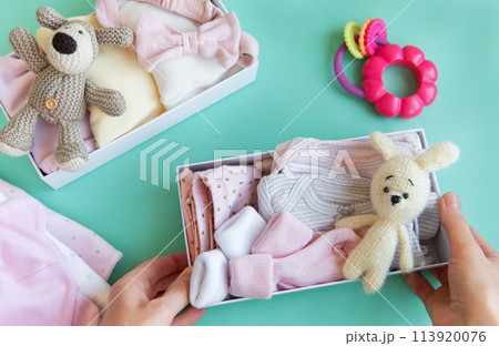 Women's hands collect children's clothes into boxes. Women's hands collect children's clothes into boxes. 113920076