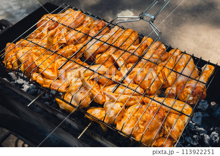 BBQ picnic time Roasted chicken legs and wings on grill. Grilling meat on outdoor grill grid tasty barbeque chicken steak with smoke flames juicy meat in the backyard 113922251