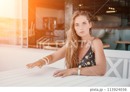 Happy woman portrait in cafe. Boho chic fashion style. Outdoor photo of young happy woman with long hair, sunny weather outdoors sitting in modern cafe. 113924036