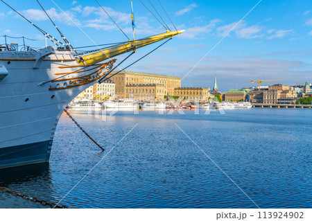 The historic Af Chapman, a full-rigged ship, is moored in Stockholm harbor with city buildings, Royal Palace and clear skies in the background. Stockholm, Sweden 113924902