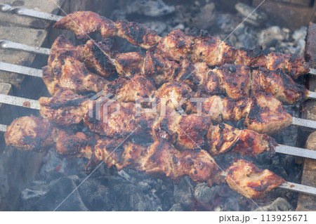 Food being grilled on skewers, creating a delicious Souvla recipe over charcoal 113925671