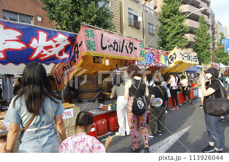 縁日の露店が通行止めの交差点の信号まで続く。楽しく露天を眺めながら嬉しそうに食べ歩く 113926044