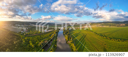 Aerial view of Lahovice Bridge spanning the Berounka River, with Prague cityscape in the distance during golden hour, casting warm light across the landscape. Prague, Czechia Aerial view of Lahovice Bridge spanning the Berounka River, with Prague cityscape in the distance during golden hour, casting warm light across the landscape. Prague, Czechia 113926907