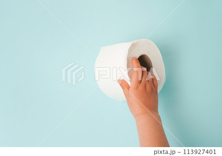 Roll of white toilet paper in child hand. blue background with copy space Roll of white toilet paper in child hand. blue background with copy space 113927401